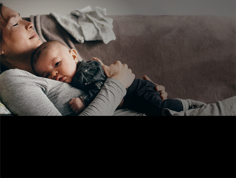 Woman with baby resting on couch.