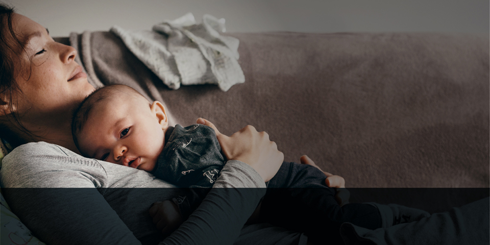 Woman with baby resting on couch.